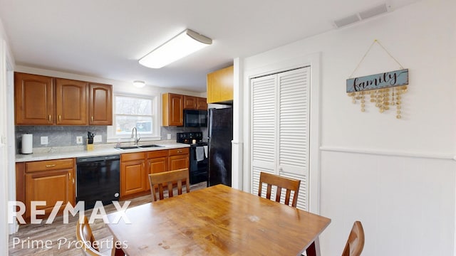 kitchen with a sink, visible vents, light countertops, backsplash, and black appliances