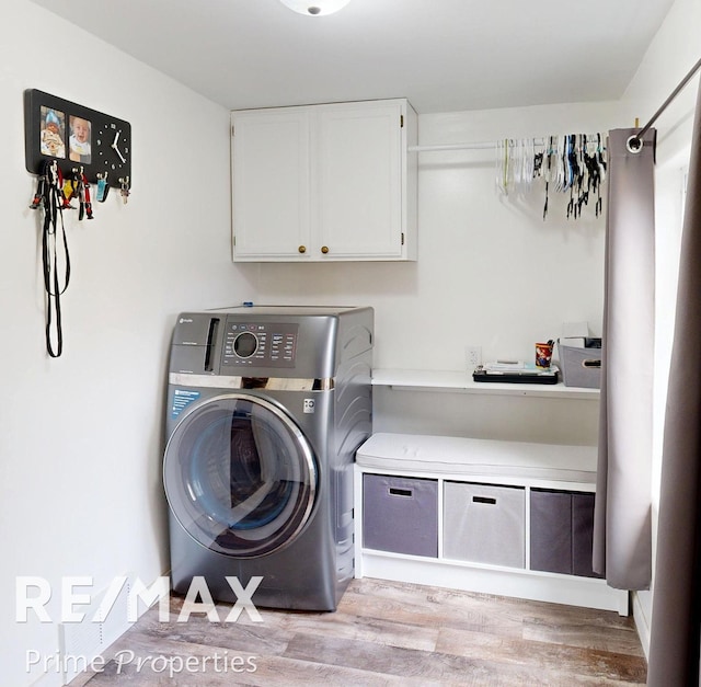 laundry room with washer / clothes dryer, cabinet space, and light wood finished floors