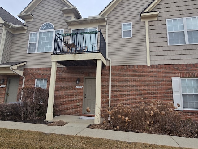 view of front facade with brick siding and a balcony