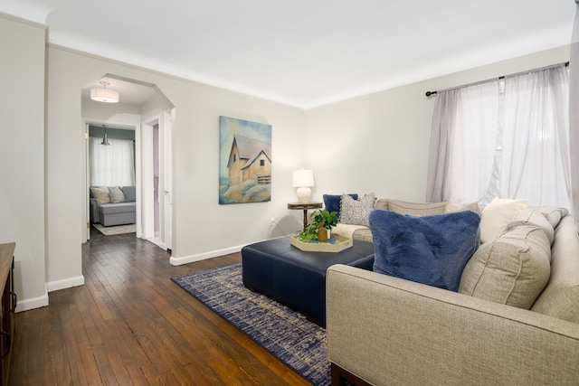 living area with arched walkways, hardwood / wood-style flooring, and baseboards