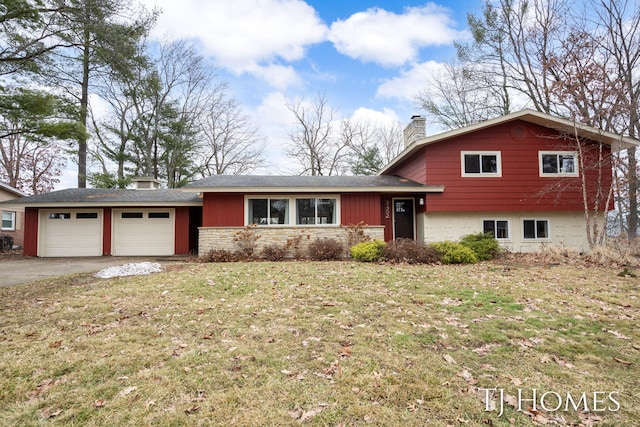 split level home featuring a front yard, driveway, a chimney, and an attached garage