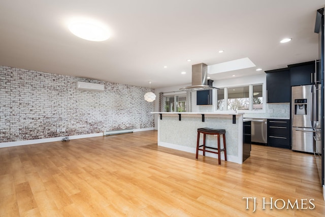 kitchen with island exhaust hood, a breakfast bar area, stainless steel appliances, light countertops, and light wood-style floors