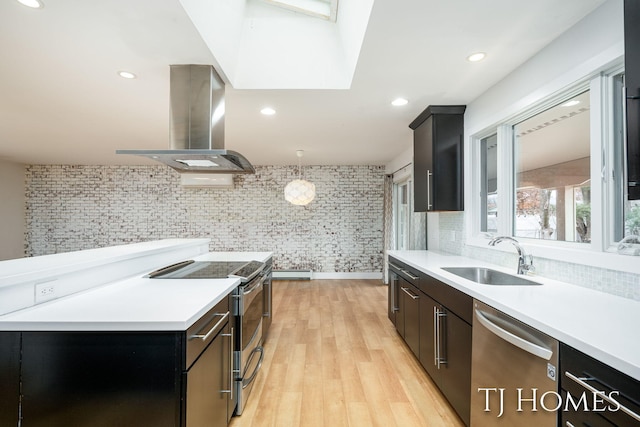 kitchen with light wood-style flooring, a sink, light countertops, appliances with stainless steel finishes, and island exhaust hood