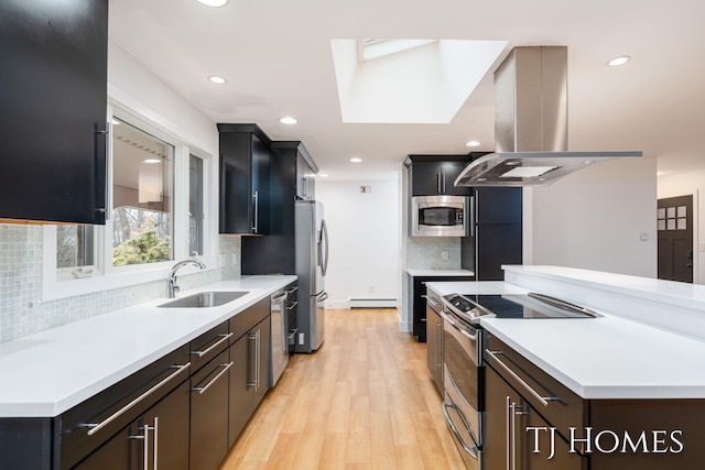 kitchen featuring a baseboard radiator, a sink, stainless steel appliances, light countertops, and island range hood