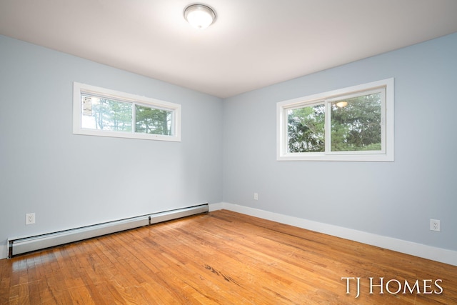 spare room featuring baseboard heating, plenty of natural light, and wood finished floors