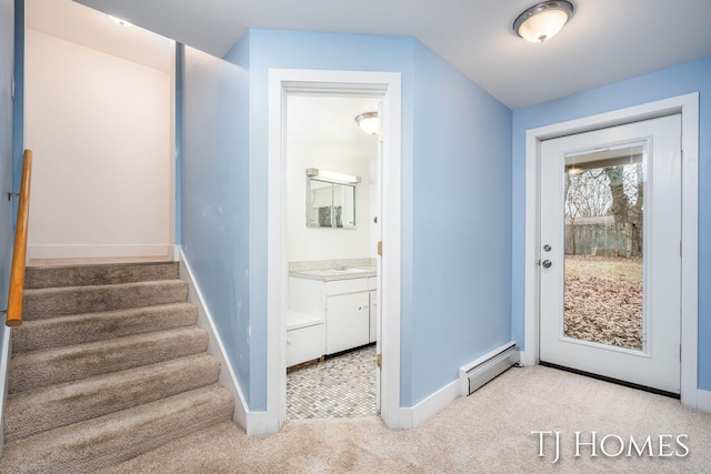 entryway with a baseboard heating unit, carpet, stairs, and baseboards