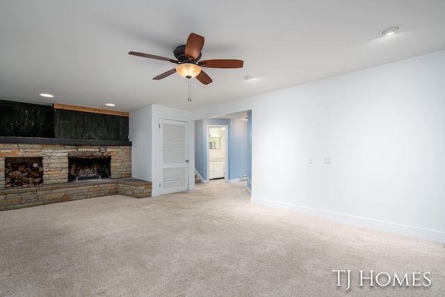 unfurnished living room featuring ceiling fan, a stone fireplace, recessed lighting, carpet floors, and baseboards