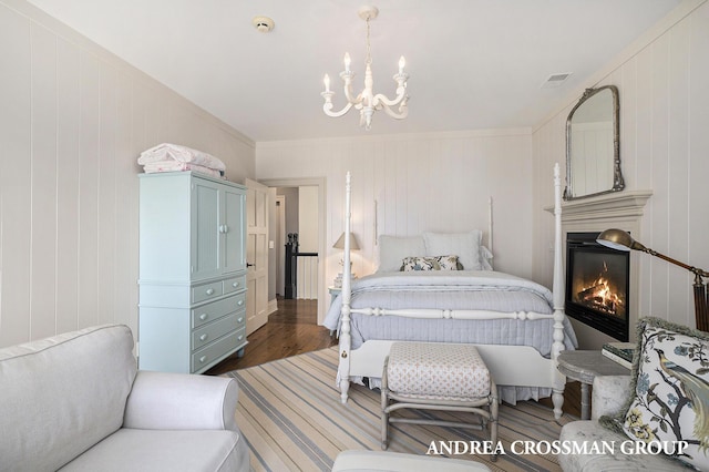 6059 Lakeshore Dr, West Olive, MI 49460 - bedroom featuring an inviting chandelier, visible vents, wood finished floors, and a glass covered fireplace