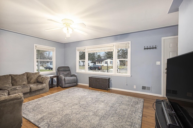 living area with a ceiling fan, visible vents, baseboards, and wood finished floors