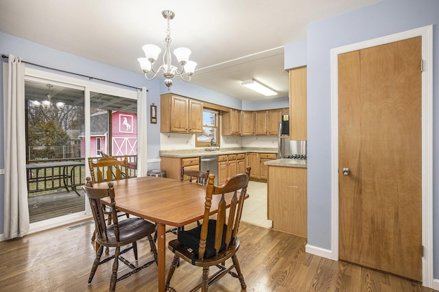 dining space featuring light wood-style flooring, a chandelier, and baseboards