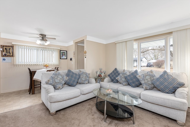 living area with carpet, ornamental molding, a ceiling fan, and tile patterned floors