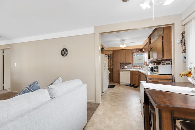 kitchen with white appliances, a ceiling fan, light countertops, backsplash, and brown cabinetry