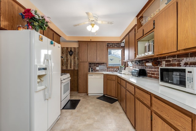 kitchen with white appliances, a sink, light countertops, backsplash, and brown cabinets