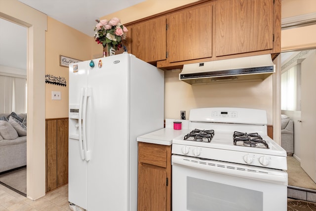 kitchen with brown cabinets, light countertops, open floor plan, white appliances, and under cabinet range hood