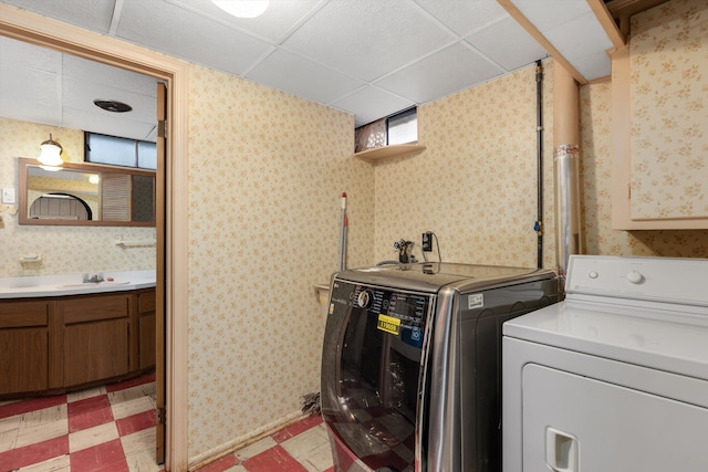 laundry area with a sink, light floors, washing machine and clothes dryer, and wallpapered walls