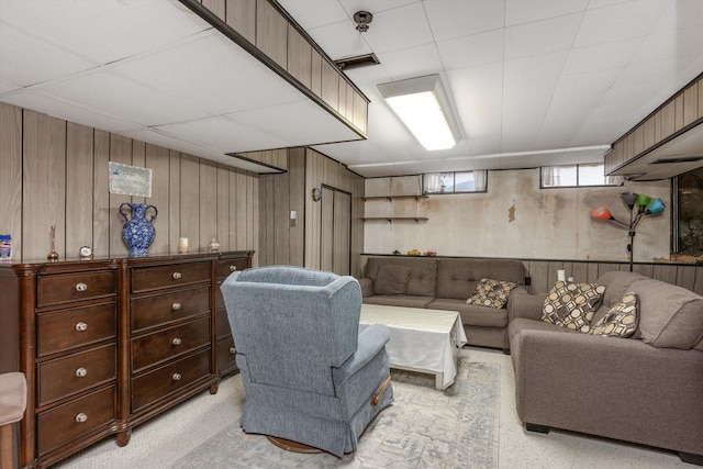 living area featuring wooden walls and a drop ceiling