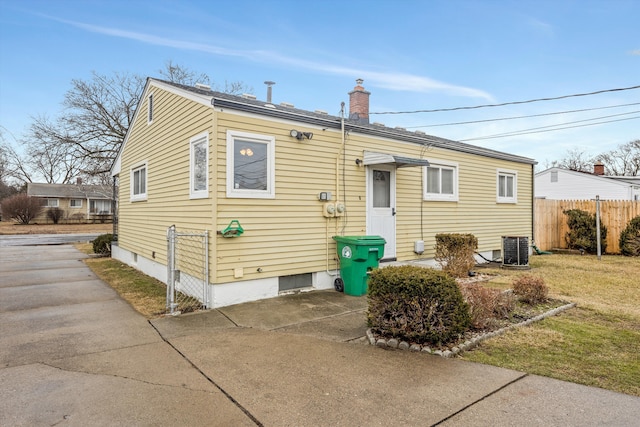 back of property featuring a yard, a chimney, fence, and central air condition unit