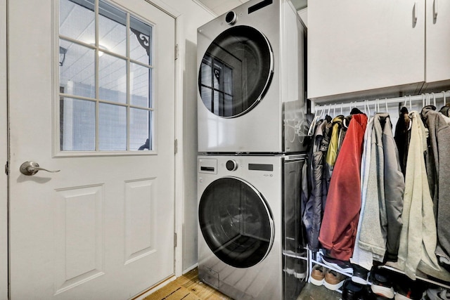 clothes washing area featuring stacked washer and dryer, light wood-type flooring, and laundry area