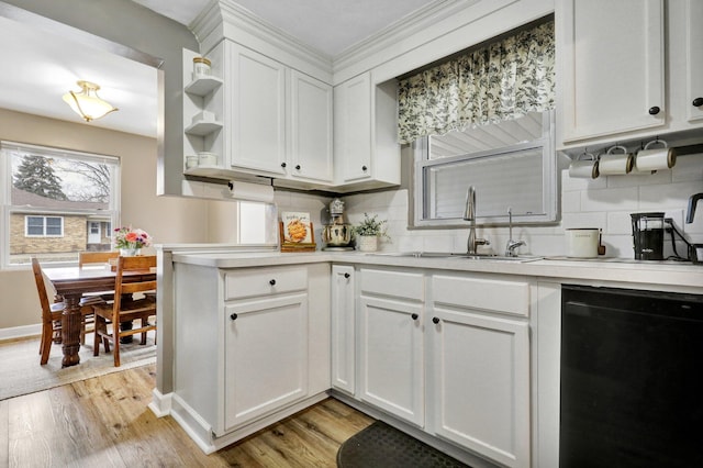 kitchen featuring black dishwasher, light countertops, a sink, and light wood-style flooring