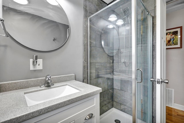 bathroom featuring wood finished floors, a stall shower, vanity, and visible vents