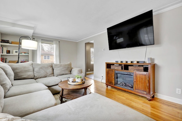 living area featuring ornamental molding, wood finished floors, and baseboards