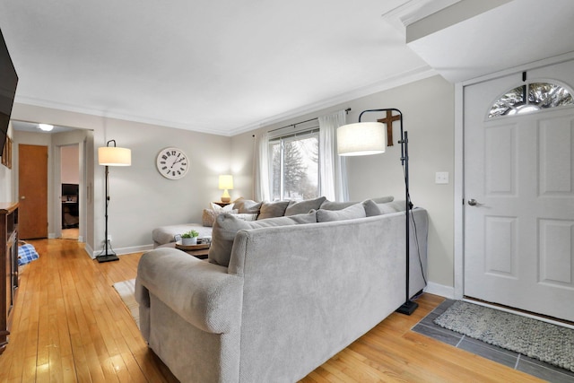 living area featuring baseboards, ornamental molding, and light wood-style floors