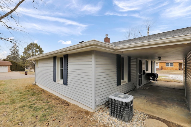 view of side of home featuring a chimney and central air condition unit