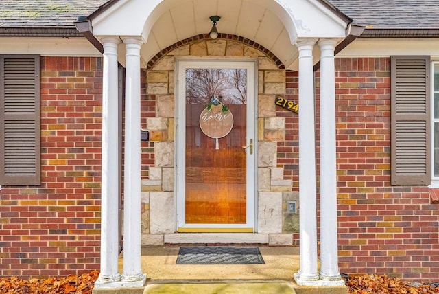 entrance to property with brick siding and roof with shingles