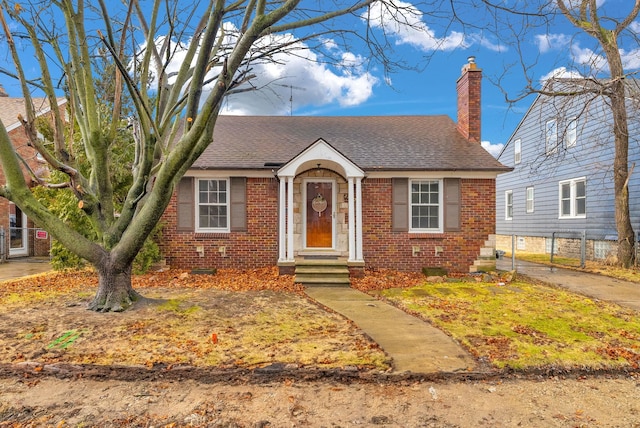 view of front of property with brick siding, a chimney, and roof with shingles