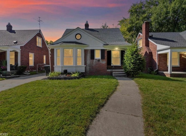 bungalow with brick siding, a yard, and a chimney