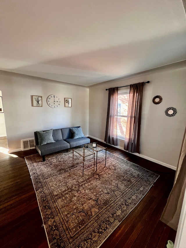 living area with baseboards, visible vents, and wood finished floors