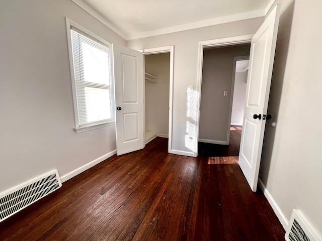 unfurnished bedroom with hardwood / wood-style flooring, baseboards, visible vents, and a closet