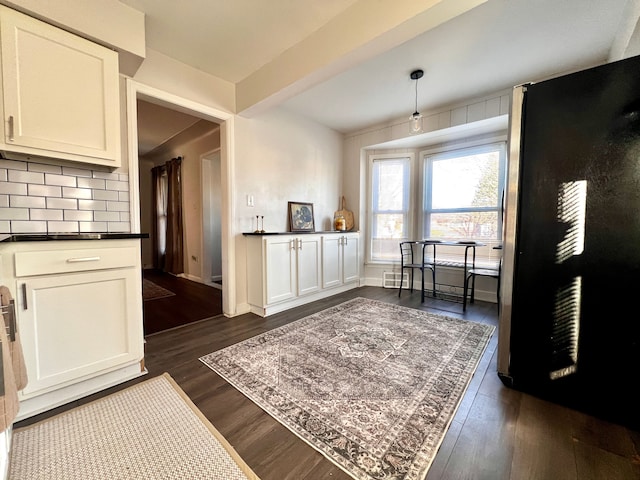 interior space featuring dark wood-style floors, beamed ceiling, and baseboards