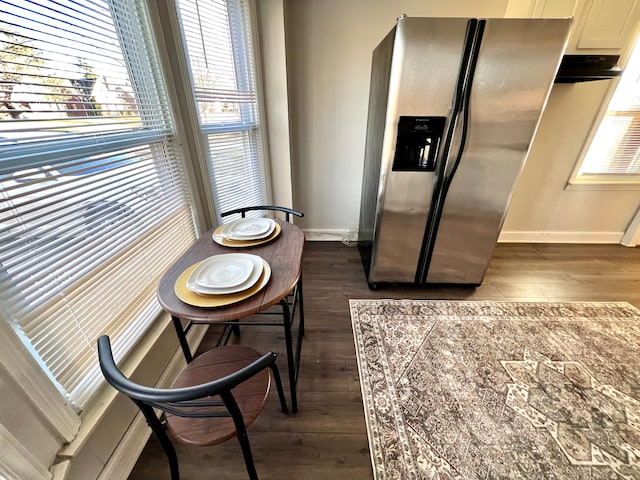 kitchen featuring dark wood-type flooring, stainless steel fridge, and baseboards