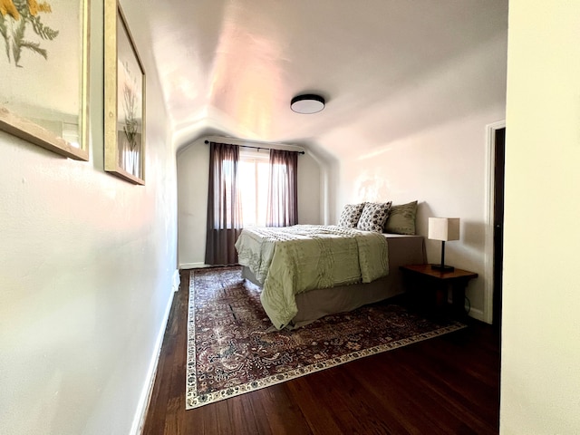 bedroom featuring lofted ceiling, wood-type flooring, and baseboards