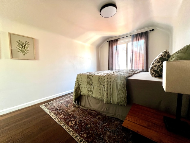 bedroom with lofted ceiling, baseboards, and wood finished floors