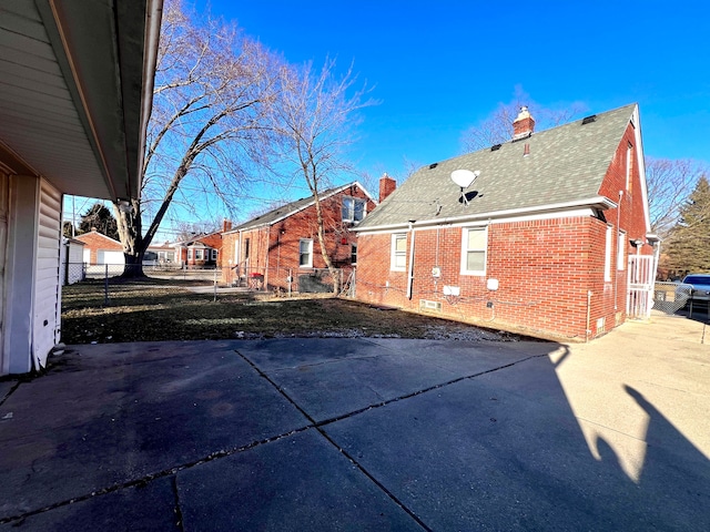 back of house with brick siding, a shingled roof, fence, crawl space, and a chimney