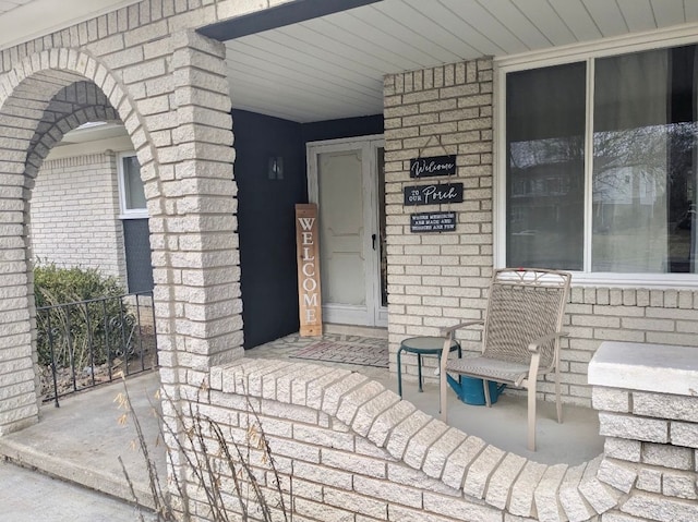 view of exterior entry with covered porch and brick siding