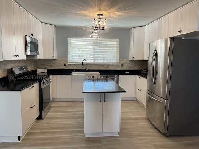 kitchen featuring dark countertops, a kitchen island, stainless steel appliances, and a sink