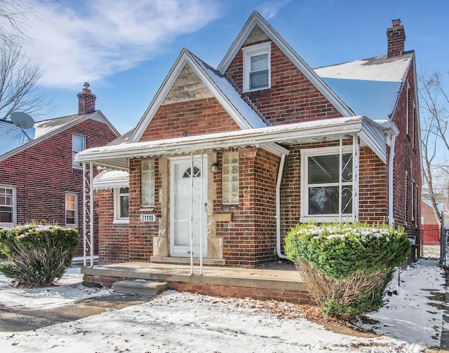 view of front of house with covered porch, brick siding, and a chimney