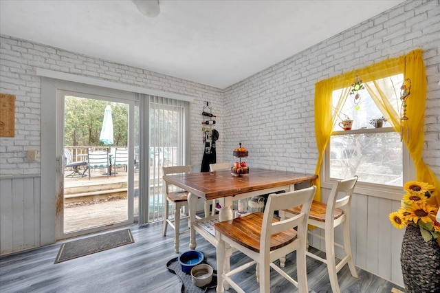 dining room with brick wall and wood finished floors