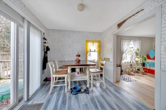 dining room with brick wall and wood finished floors