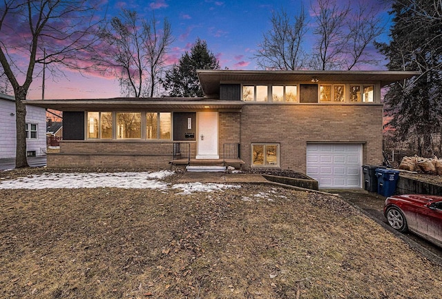 split level home with an attached garage and brick siding