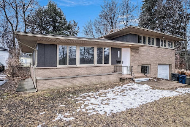 split level home featuring an attached garage, board and batten siding, and brick siding