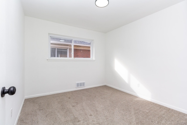 carpeted spare room with visible vents and baseboards