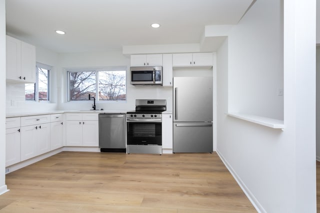 kitchen with appliances with stainless steel finishes, light wood-style flooring, and white cabinets