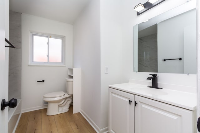 bathroom featuring toilet, hardwood / wood-style flooring, baseboards, and vanity