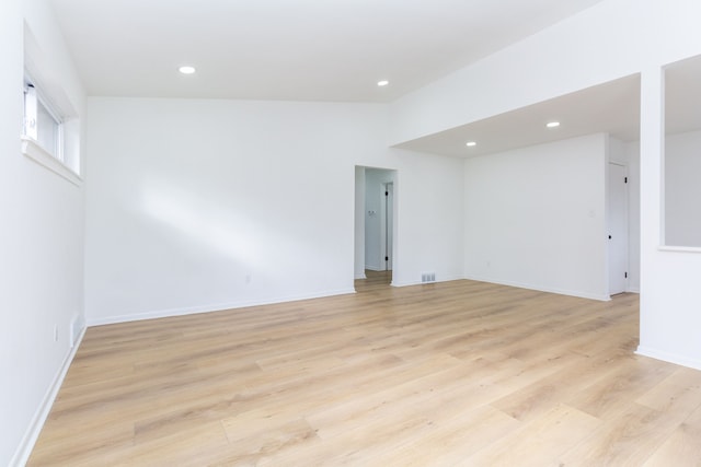 empty room with lofted ceiling, recessed lighting, visible vents, light wood-style floors, and baseboards