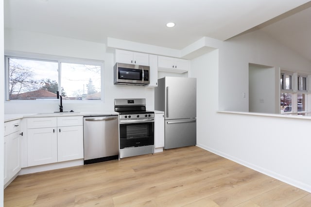 kitchen with stainless steel appliances, light countertops, light wood-style flooring, white cabinets, and a sink