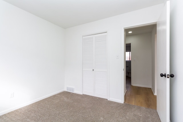 unfurnished bedroom featuring carpet, a closet, visible vents, and baseboards